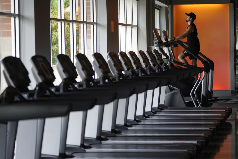 Evan Leedy exercises at Burn Fitness in Rochester Hills, Mich., Monday, June 21, 2021. Michigan is fully open again. After facing 15 months of capacity restrictions and being hit by the country’s worst surge of coronavirus infections this spring, restaurants, entertainment businesses and other venues can operate at 100% occupancy starting Tuesday. (AP Photo/Paul Sancya)