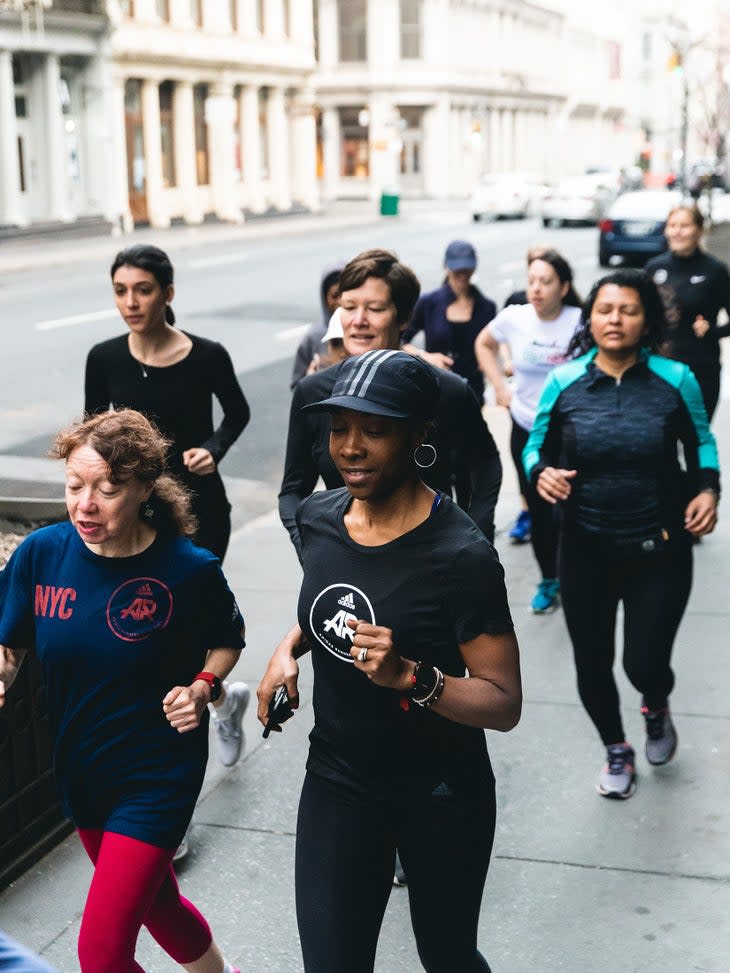 an inclusive running group of women run down a city street