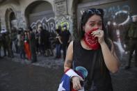 An anti-government protester cries from the effects of tear gas, during clashes with police in Santiago, Chile, Tuesday, Oct. 22, 2019. Chile's government said Tuesday that 15 people have been killed in five days of rioting, arson and violent clashes that have almost paralyzed the country. (AP Photo/Rodrigo Abd)