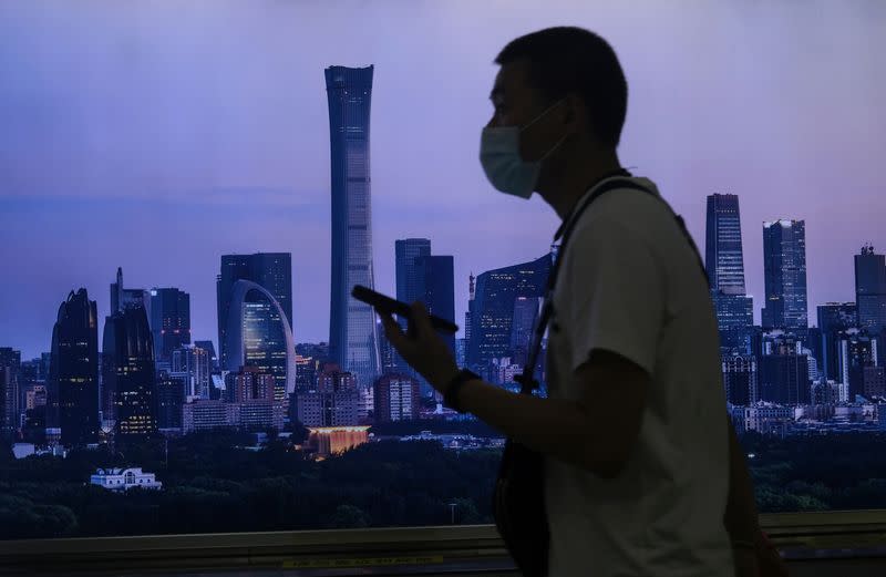 Man wearing a face mask walks past a billboard showing Beijing's city skyline at a subway station, following the coronavirus disease (COVID-19) outbreak, in Beijing