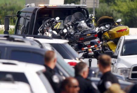 Police officers look at several motorcycles, which have been loaded onto a wrecker for removal from the Twin Peaks restaurant, where nine members of a motorcycle gang were shot and killed, in Waco, Texas May 19, 2015. REUTERS/Mike Stone