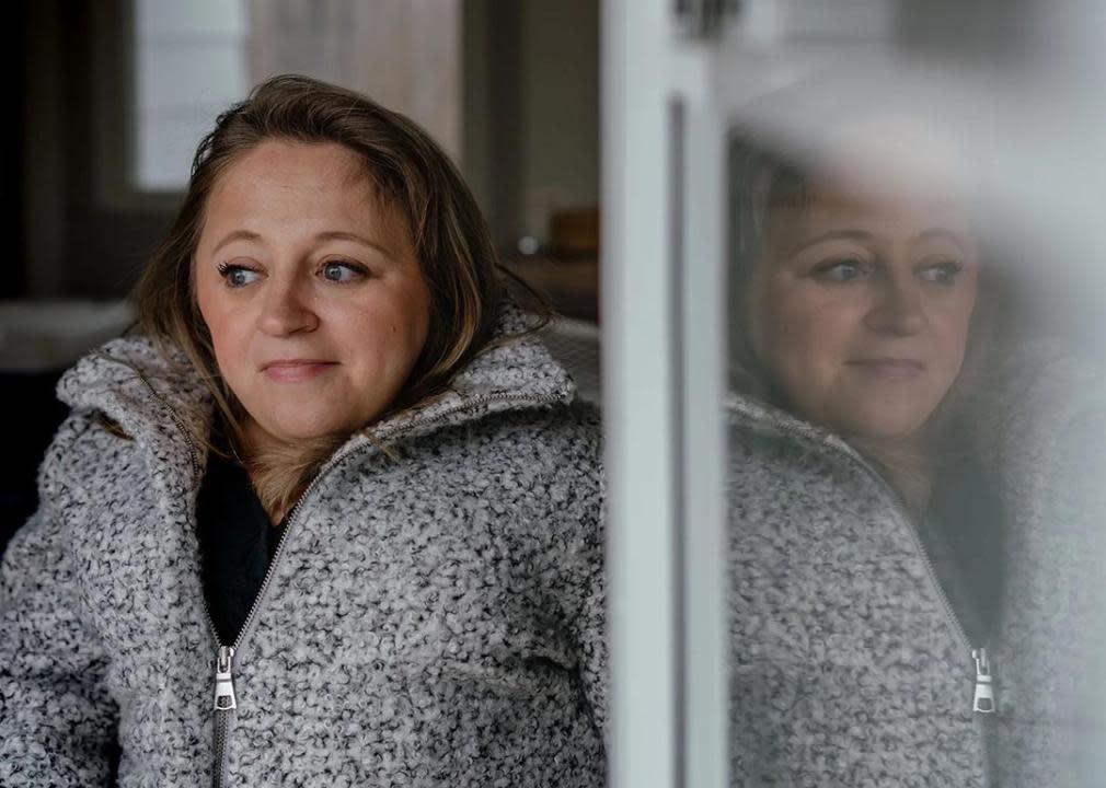 Portrait of Emily Voorde on left side with her image reflection visible on the glass on the right side