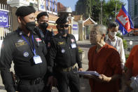 Theary Seng, right, a Cambodian-American lawyer, dressed in a prison-style orange outfit, talks with court securities as she arrived at Phnom Penh Municipal Court in Phnom Penh, Cambodia, Tuesday, Jan. 4, 2022. Cambodian security forces on Tuesday briefly detained Theary, a prominent rights activist, as she walked barefoot near the prime minister’s residence in Phnom Penh, wearing the orange outfit and Khmer Rouge-era ankle shackles. She was released, shortly afterwards, and arrived at the Phnom Penh court for the resumption of her trial on treason charges. (AP Photo/Heng Sinith)