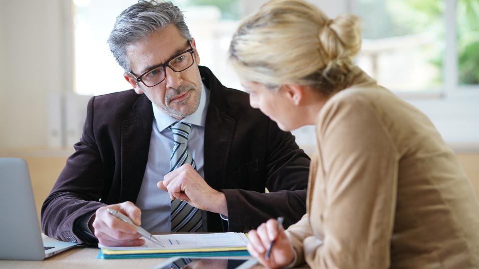 older man next to woman pointing to a paper