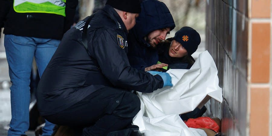 Specialists of the State Emergency Service and the National Police near a man who found a loved one among the dead in Kyiv, February 7, 2024