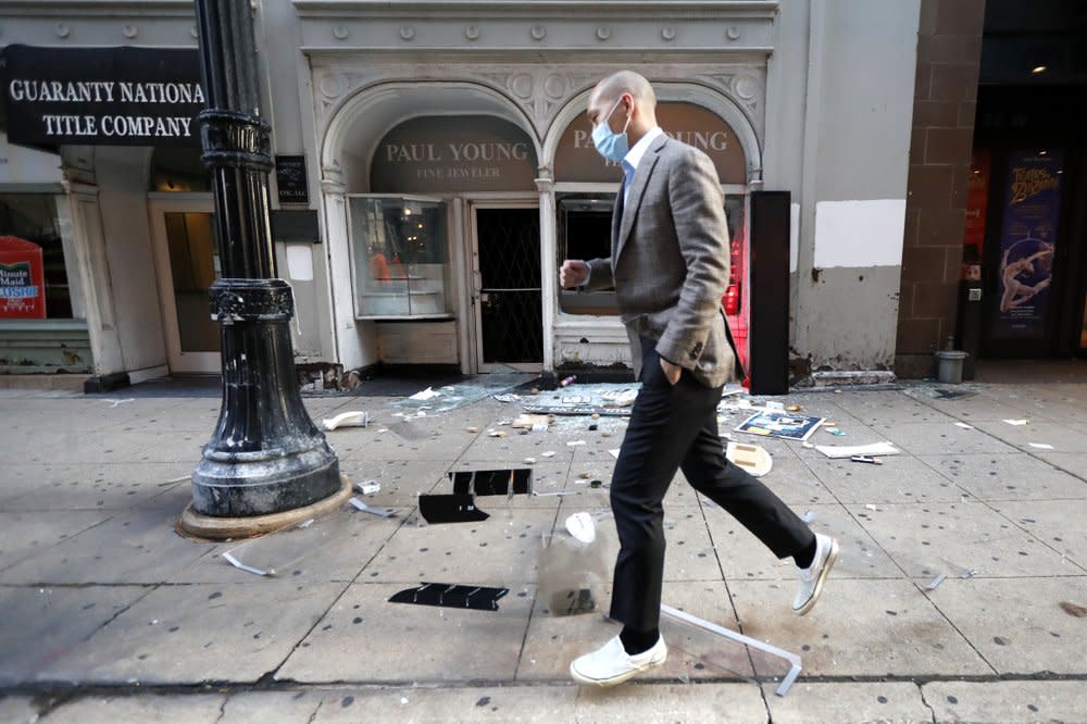 A pedestrian hops over debris Monday, Aug. 10, 2020, after a jewelry store was vandalized in Chicago’s famed Loop. (AP Photo/Charles Rex Arbogast)