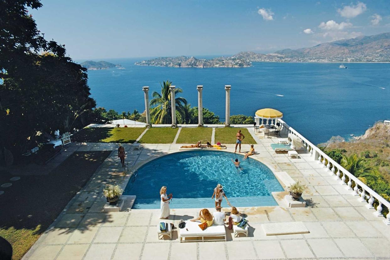 A group of people swim in a pool overlooking the water in Acapulco, Mexico