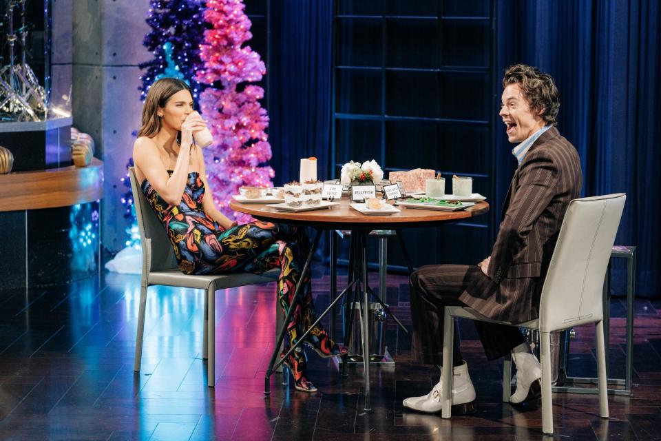 Kendall Jenner (left) and Harry Styles (right) sit at a table eating an array of food