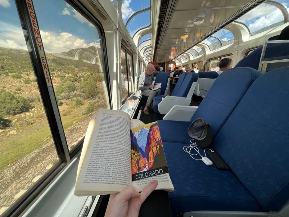 person holding a book open while riding on an amtrak train