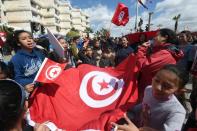 Tunisians wave their national flag during a march against extremism outside the Bardo Museum in Tunis on March 29, 2015
