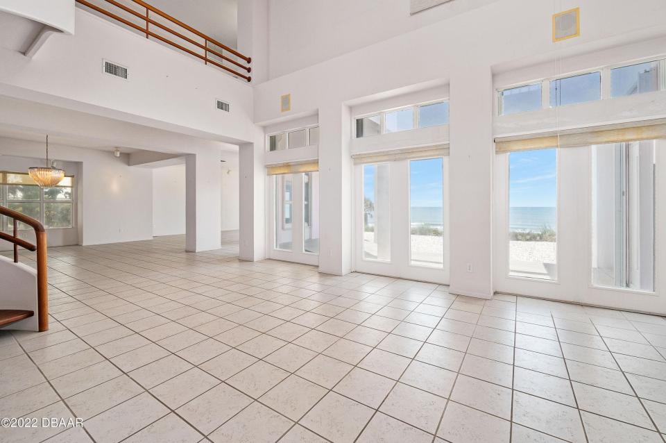 The interior shows off soaring ceilings above oversized picture windows that frame the Atlantic Ocean and tile floors that cover the main living areas.