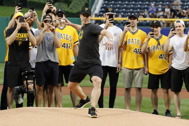 Pittsburgh Penguins captain Sidney Crosby throws out a ceremonial first pitch, as his teammates record the occasion, before a baseball game between the Pittsburgh Pirates and the Colorado Rockies in Pittsburgh, Tuesday, June 13, 2017. The Penguins were on hand to celebrate their Stanley Cup win over the Nashville Predators. (AP Photo/Gene J. Puskar)