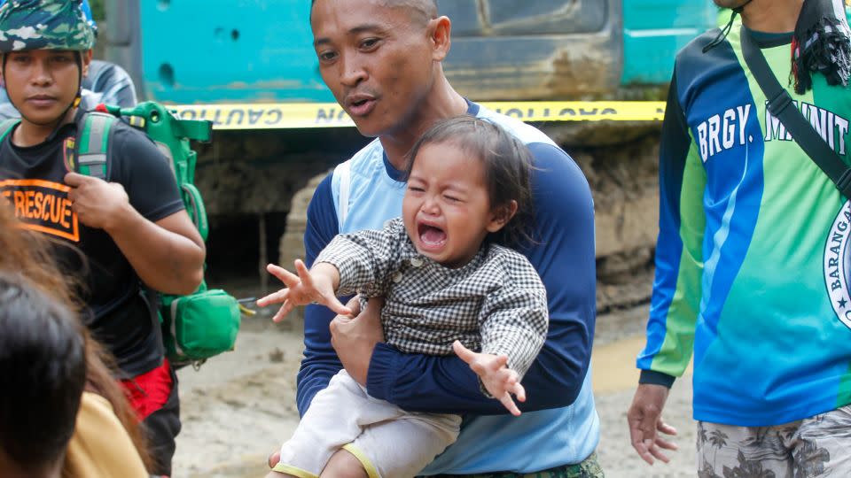 A policeman carries a baby as officials ordered mandatory evacuation from the landslide-hit village on February 8, 2024. - Jeoffrey Maitem/Anadolu/Getty Images