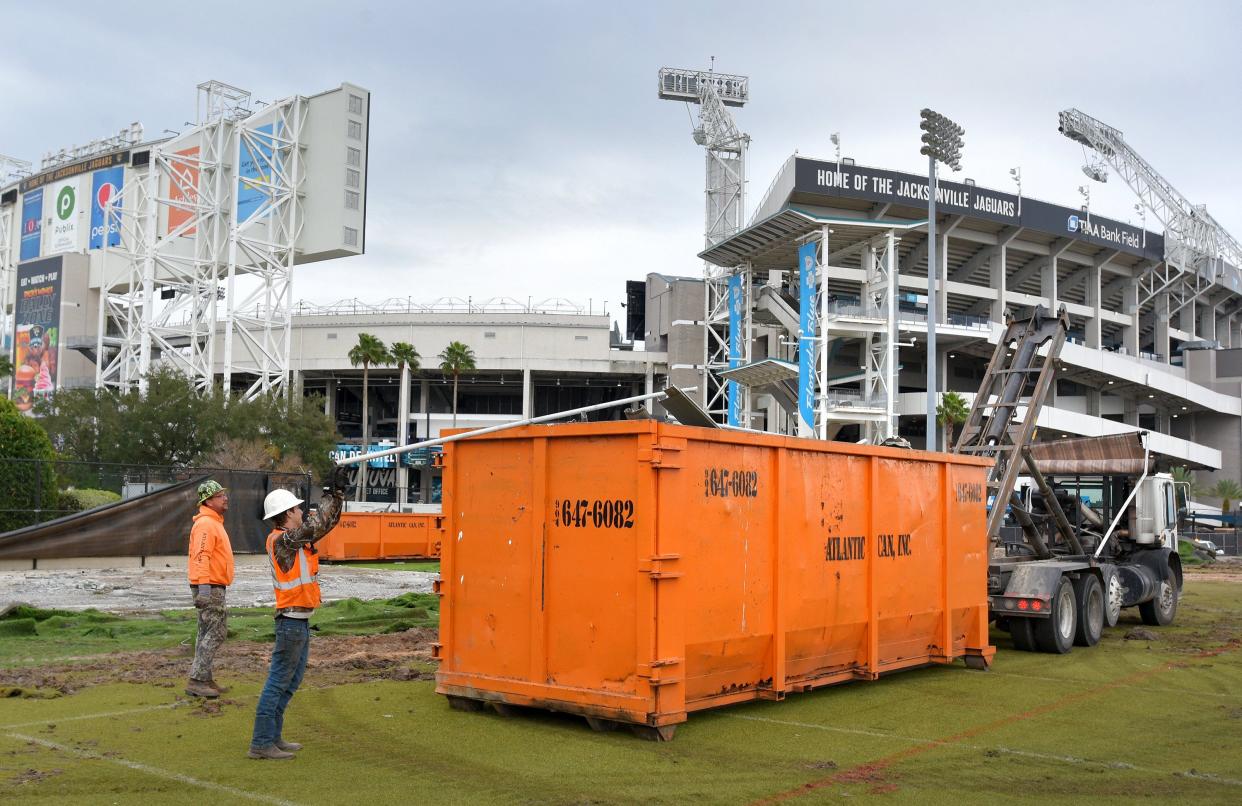 Workers clean up scraps of the bleachers from the old practice fields, putting them into a dumpster outside TIAA Bank Field Wednesday afternoon. Subcontractors for Haskell have begun site preparation on the Jacksonville Jaguars old practice fields outside TIAA Bank Field to start construction of the new Jaguars Sports Performance Center there. Wednesday, January 26, 2022. [Bob Self/Florida Times-Union]