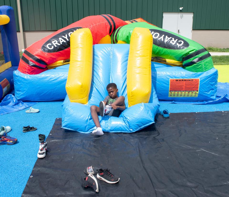 Robert White Jr. puts his shoes back on playing on the inflatable slide and bounce house Saturday at the King Kennedy Community Center in Ravenna.
