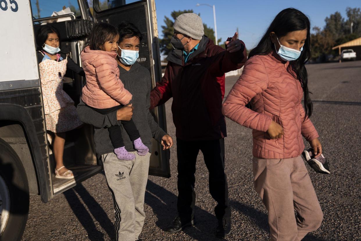 From left, Emili Buitrago, 7, William Cofre, Jennifer, 2, and his wife Blanca Ninasunta exit a bus carrying migrants while directed to Iglesia Cristiana El Buen Pastor by Pastor Hector Ramirez, at center, on Thursday, Dec. 22, 2022, in Mesa. The family fled Ecuador and, along with migrants from various other Central and South American countries, was transported to the church to help them get to their final destinations in the U.S.