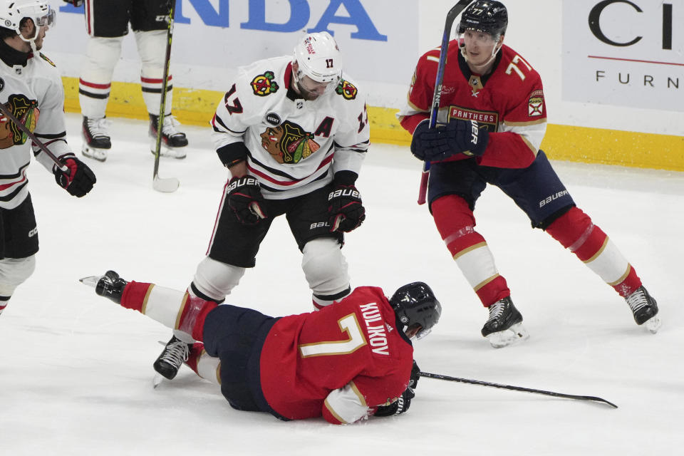 Chicago Blackhawks left wing Nick Foligno (17) gets called for a penalty after knocking down Florida Panthers defenseman Dmitry Kulikov (7) as defenseman Niko Mikkola (77) follows on the play during the second period of an NHL hockey game Sunday, Nov. 12, 2023, in Sunrise, Fla. (AP Photo/Jim Rassol)