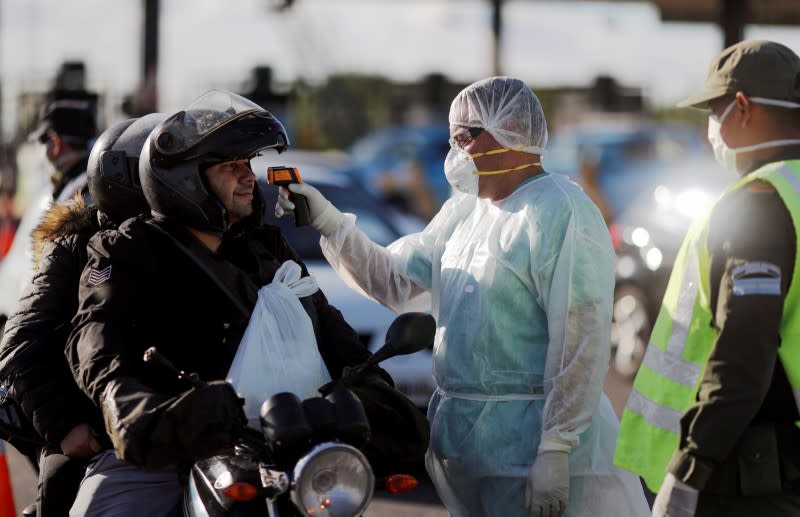 A health worker takes the temperature of a driver for precaution due to coronavirus disease (COVID-19), in Buenos Aires