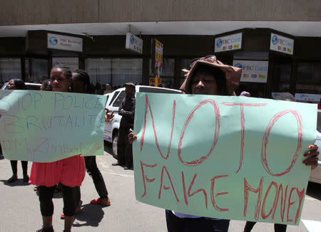 Protesters hold placards during a demonstration against the new ‘bond notes’ that came into circulation this week in an attempt to ease chronic cash shortages, in the capital Harare, Zimbabwe, November 30, 2016. REUTERS/Philimon Bulawayo