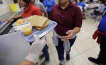 Migrant teens eat lunch at a "tender-age" facility for babies, children and teens, in Texas' Rio Grande Valley, Thursday, Aug. 29, 2019, in San Benito, Texas. The facility offers services that include education, nutrition, hygiene, recreation, entertainment, medical, mental health and counseling, according to a U.S. Health and Human Services official. (AP Photo/Eric Gay)