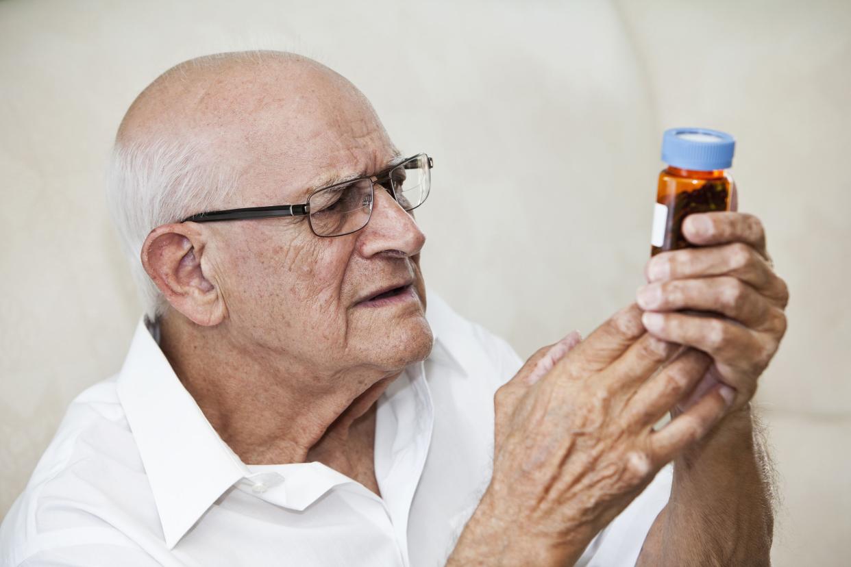 elderly man reading medicine bottle