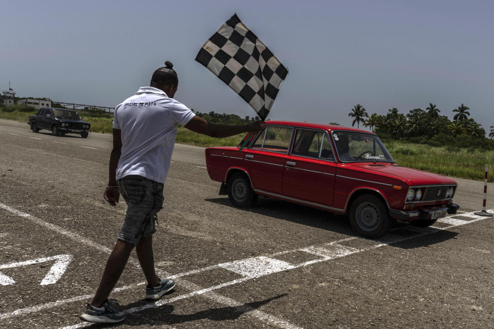 Un Lada rojo cruza la línea de meta para ganar una carrera de resistencia en una antigua pista de aterrizaje sin usar en San Nicolás de Bari, Cuba, el domingo 23 de julio de 2023. (Foto AP/Ramón Espinosa)