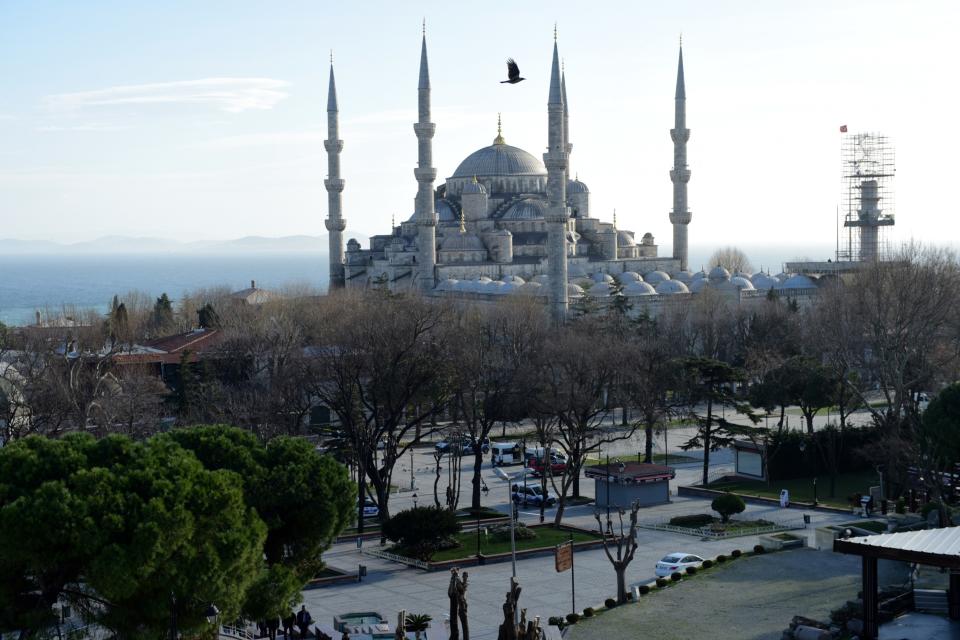 TOPSHOT - A bird flies over the Blue Mosque after a blast in Istanbul's tourist hub of Sultanahmet on January 12, 2016. At least 10 people were killed and 15 wounded in a suspected terrorist attack in the main tourist hub of Turkey's largest city Istanbul, officials said. A powerful blast rocked the Sultanahmet neighbourhood which is home to Istanbul's biggest concentration of monuments and and is visited by tens of thousands of tourists every day. / AFP / BULENT KILIC        (Photo credit should read BULENT KILIC/AFP/Getty Images)
