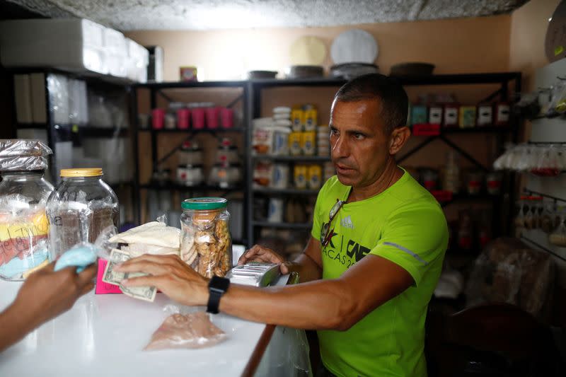 FILE PHOTO: A worker receives a dollar cash payment in a store in a market in Caracas,