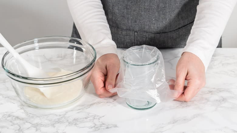 person filling piping bag over glass