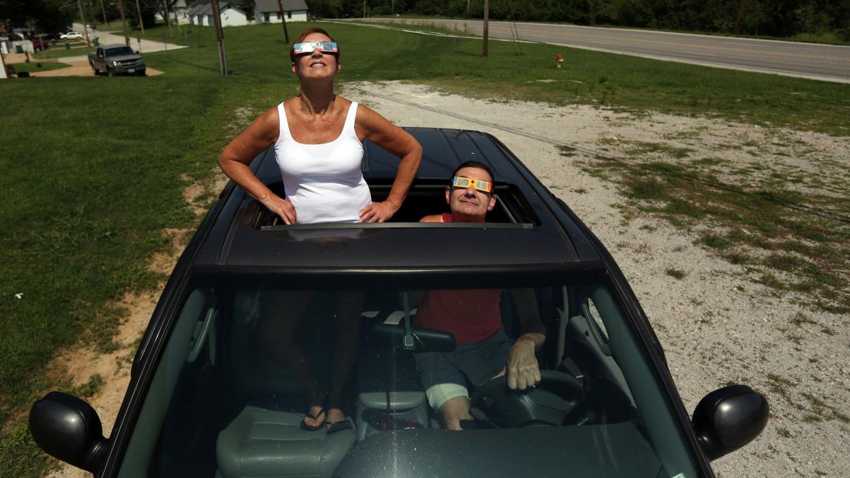  Two people watching the solar eclipse from their car. . 