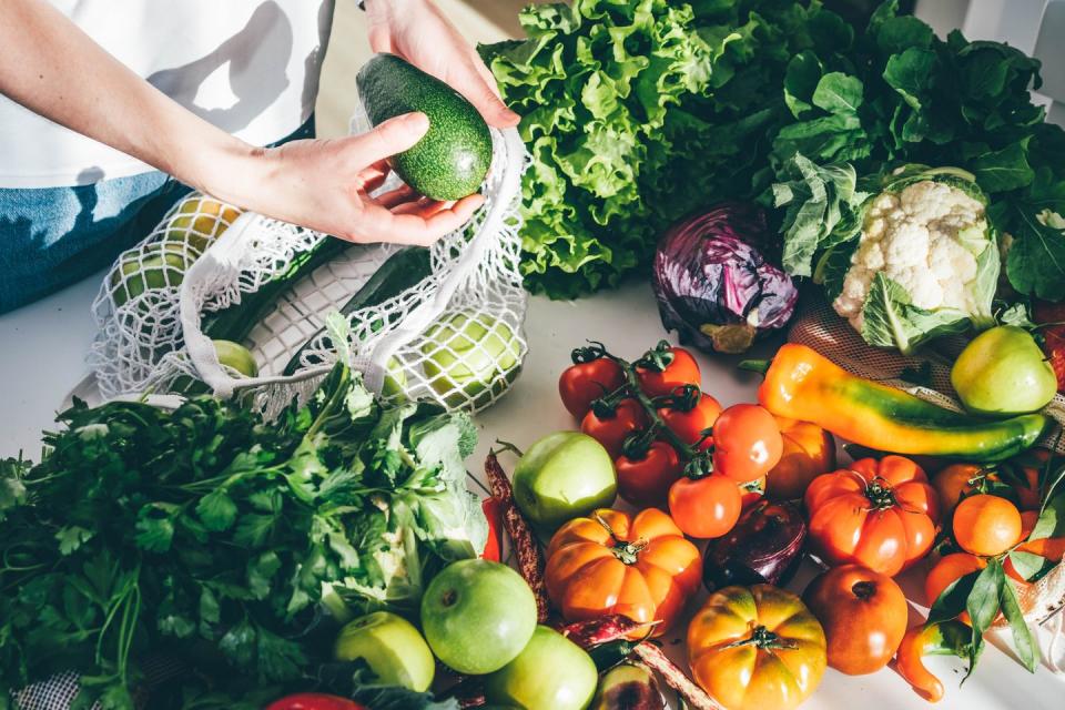 a woman choosing from a selection of fruit and vegetables