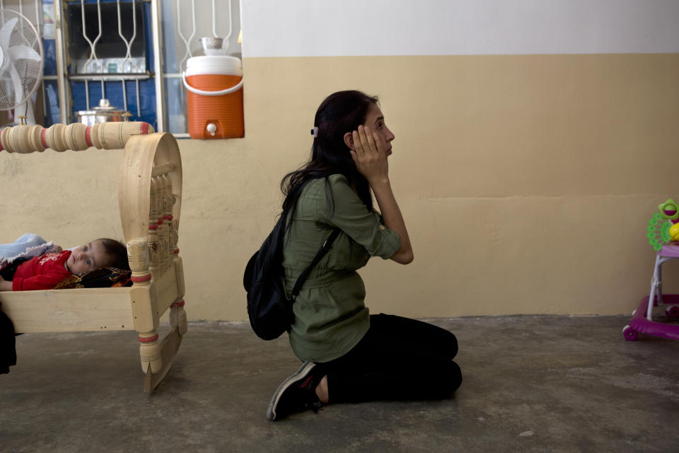 In this Aug. 31, 2019 photo, Layla Taloo reacts as she visits a room in the house where she was held along with her husband and children after Islamic State militants captured the family in 2014, in Tal Afar, Iraq. It was the last place she saw her husband. (AP Photo/Maya Alleruzzo)