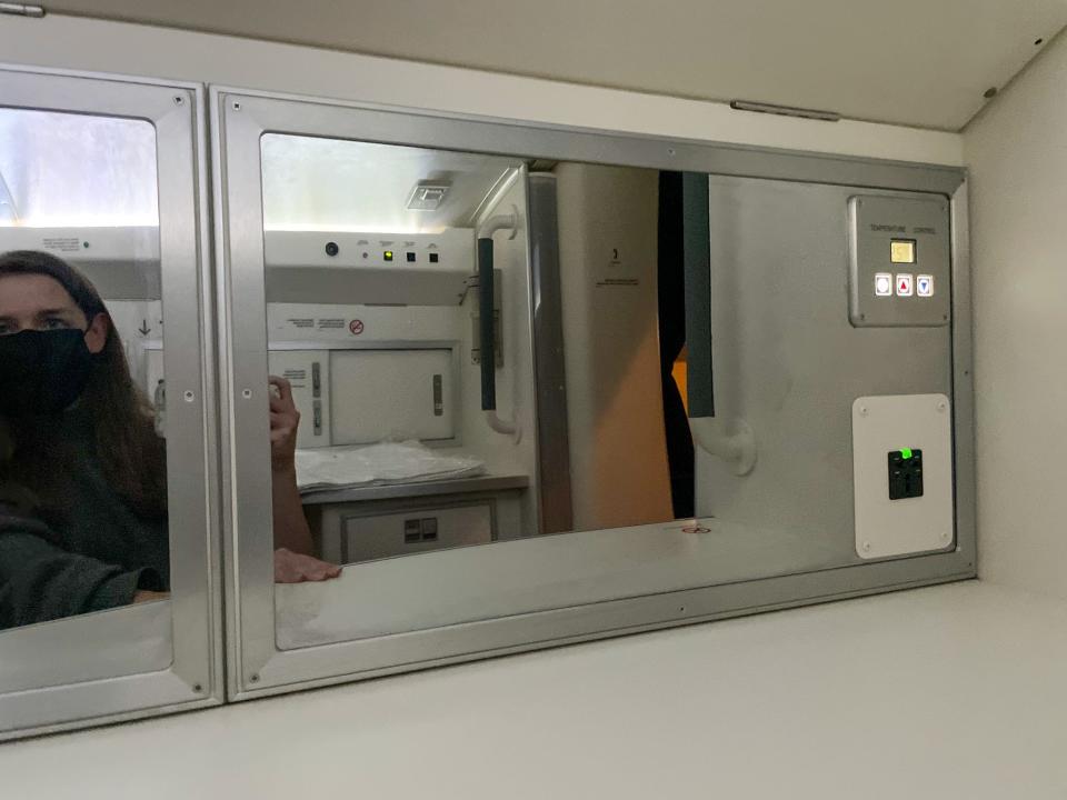 The entrance of the flight attendant's rest area has a mirror and some storage.