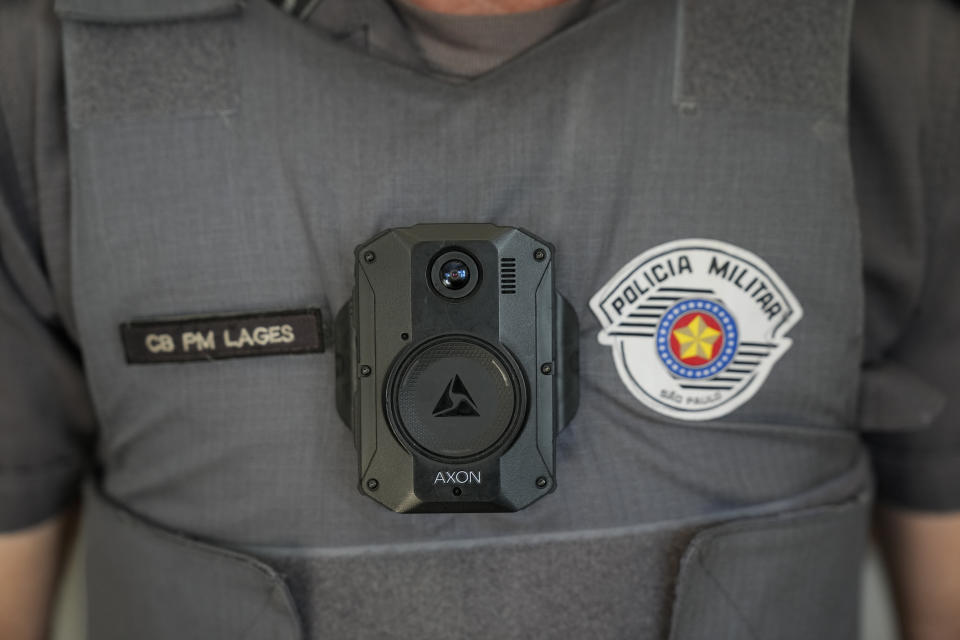 A police officer poses for a photo wearing a bulletproof vest installed with a body cam, in Sao Paulo, Brazil, Wednesday, Aug. 18, 2021. Brazil has a long history of police violence and now authorities are looking at body cameras as a way to avoid deadly incidents involving policemen. (AP Photo/Andre Penner)