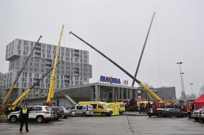 Police and rescue workers surround the Maxima supermarket in Riga, Latvia, Friday, Nov. 22, 2013. At least 32 people died, including three firefighters, after an enormous section of roof collapsed at a Latvian supermarket in the country's capital, emergency medical officials said Friday. The reason for the collapse during shopping rush-hour Thursday was still not known but rescue and police officials said that possible theories include building's design flaws and poor construction work. (AP Photo/ Roman Koksarov)