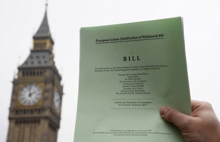 A journalist poses with a copy of the Brexit Article 50 bill, introduced by the government to seek parliamentary approval to start the process of leaving the European Union, in front of the Houses of Parliament in London, Britain, January 26, 2017. REUTERS/Toby Melville