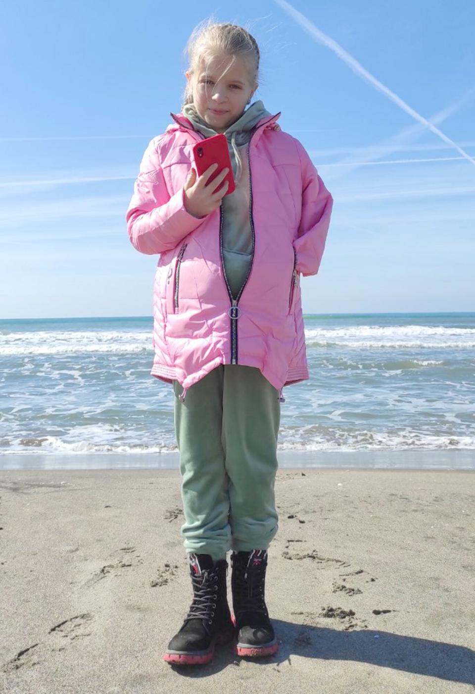 Sasha texting friends on the beach