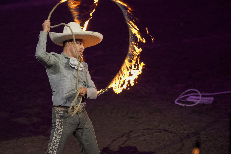 Luis Miguel Rivera performs tricks with a rope in fire at the "Jaripeo Hasta Los Huesos Tour 2024" show at the Honda Center in Anaheim, Calif., on Friday, March 29, 2024. The Grammy-winning singer songwriter Pepe Aguilar show pays tribute to the Day of the Dead, a well-known Mexican celebration. (AP Photo/Damian Dovarganes)