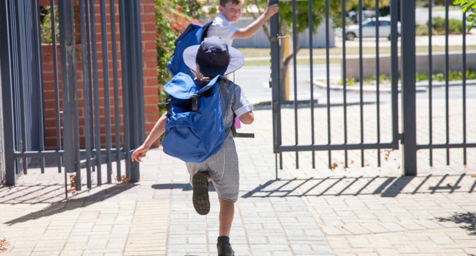 A young girl runs towards the school gate. 