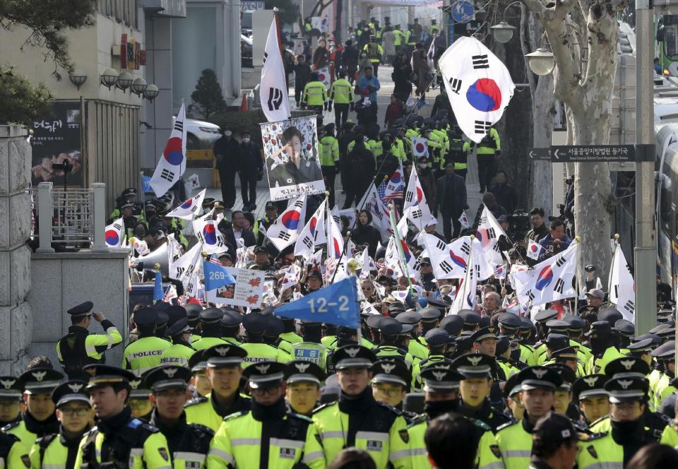 Supporters of South Korean ousted President Park Geun-hye wave national flags and picture of Park outside of a prosecutors' office in Seoul, South Korea, Tuesday, March 21, 2017. Park said she was "sorry" to the people as she arrived Tuesday at a prosecutors' office for questioning over a corruption scandal that led to her removal from office. (AP Photo/Lee Jin-man)