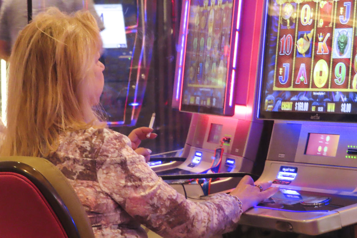 A gambler smokes while playing a slot machine at the Hard Rock casino in Atlantic City, N.J., on Aug. 8, 2022. (AP Photo/Wayne Parry)