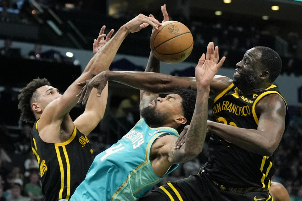 Charlotte Hornets center Nick Richards vies for the ball between Golden State Warriors forward Trayce Jackson-Davis, left, and forward Draymond Green during the second half of an NBA basketball game on Friday, March 29, 2024, in Charlotte, N.C. (AP Photo/Chris Carlson)