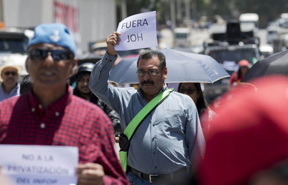 A man holds a sign that reads in Spanish: "Get out Juan Orlando Hernandez" during a protest against Honduras' president in Tegucigalpa, Honduras, Friday, Aug. 23, 2019. Hernandez was losing the ballot tally when a reported computer glitch stopped vote counting on Nov. 26, 2017, and when it came back to life hours later, Hernandez was winning, leading many to suspect electoral fraud, something the government denies. (AP Photo/Eduardo Verdugo)