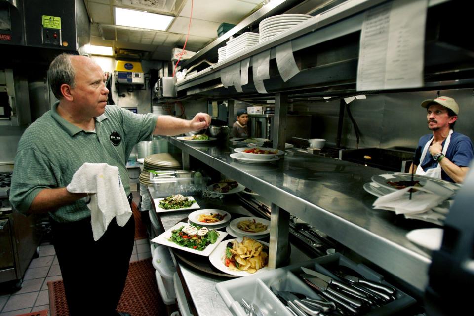 Randy Rayburn, left, owner of Sunset Grill in Hillsboro Village, set up the orders in the kitchen Oct. 17, 2006 during the lunch crowd. Cookers are Al Rubio, center, and Randy McClendon.