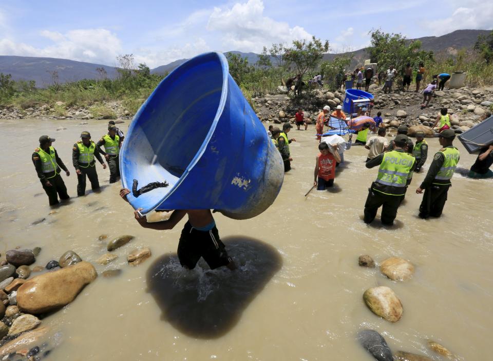 Colombianos cargan sus pertenencias a través del río Táchira. REUTERS/Jose Miguel Gomez