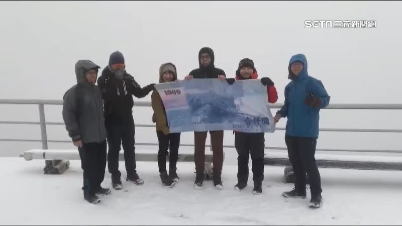 有山友自備千元大鈔毛巾，和玉山雪景拍下紀念照片。