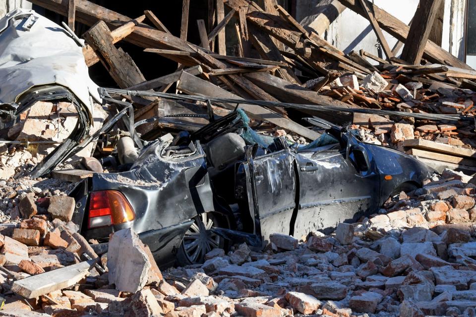 This photograph taken on December 29, 2020, shows the wreckage of a car and damaged buildings in Petrinja, some 50kms from Zagreb, after the town was hit by an earthquake of the magnitude of 6,4. - The tremor, one of the strongest to rock Croatia in recent years, collapsed rooftops in Petrinja, home to some 20,000 people, and left the streets strewn with bricks and other debris. Rescue workers and the army were deployed to search for trapped residents, as a girl was reported dead. (Photo by DENIS LOVROVIC / AFP) (Photo by DENIS LOVROVIC/AFP via Getty Images)