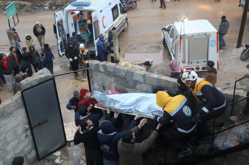 Rescuers carry the body of a casualty at the site of a damaged building, following an earthquake, in rebel-held Azaz