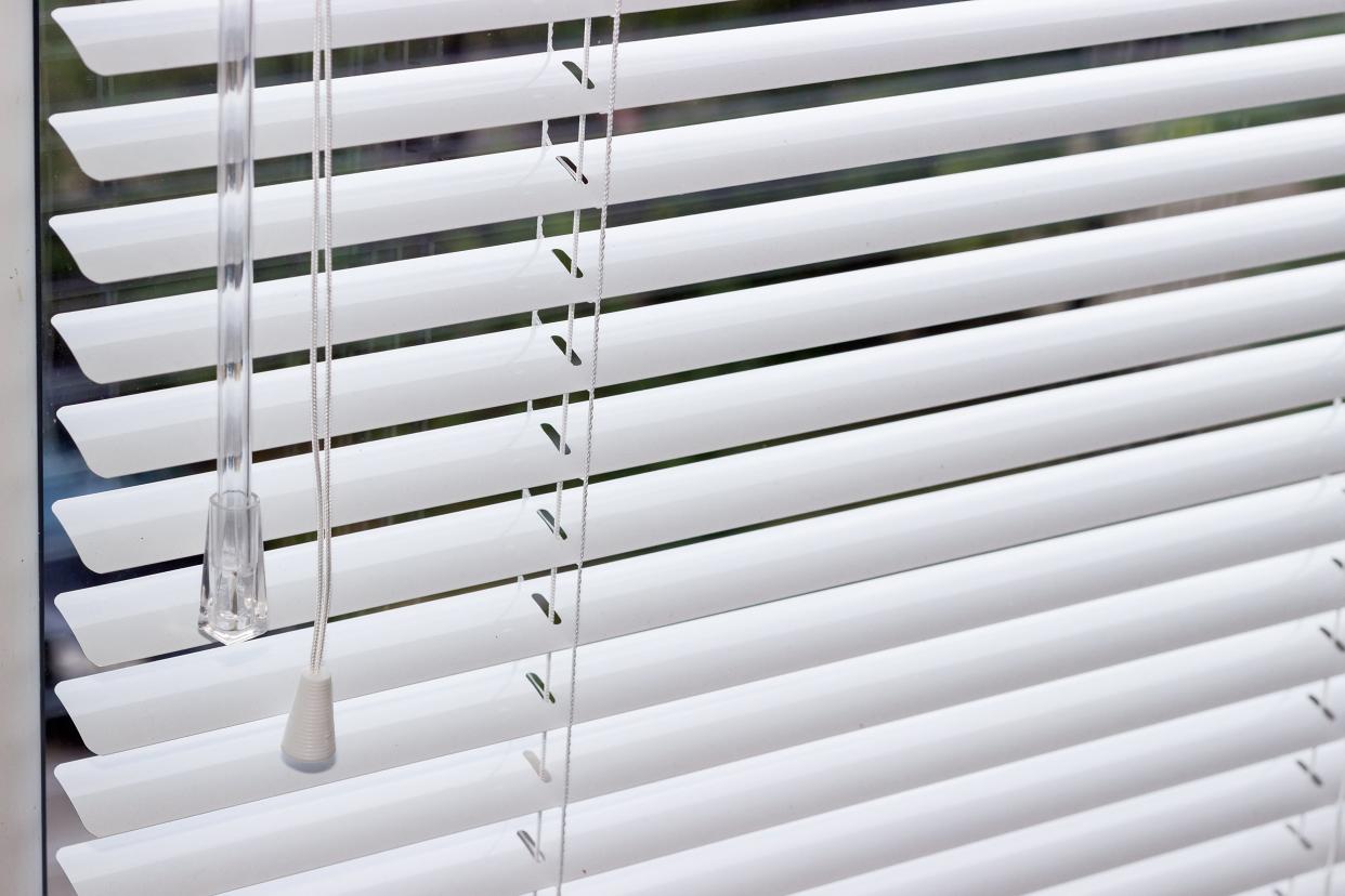 fragment of the white Venetian blinds with manual control