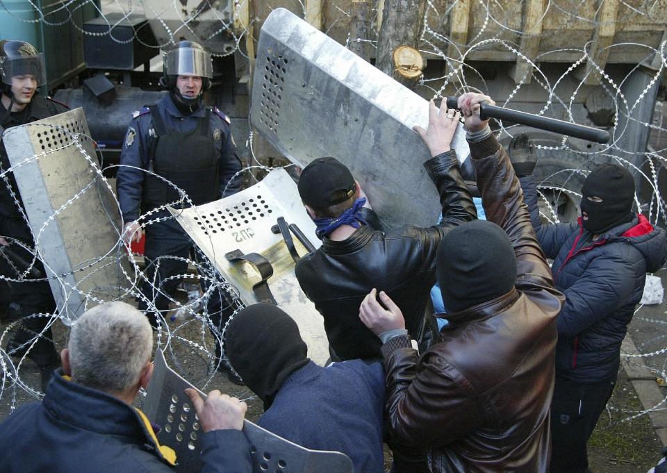 People clash with police at the regional administration building in Donetsk, Ukraine, Sunday, April 6, 2014. In Donetsk a large group of people surged into the provincial government building and smashed windows. A gathering of several hundred, many of them waving Russian flags, then listened to speeches delivered from a balcony emblazoned with a banner reading “Donetsk Republic.” (AP Photo/Alexander Ermochenko)